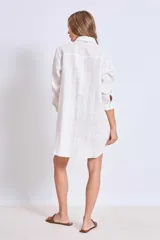Vestido camisero corto color crudo, de lino, con cuello camisero, mangas largas y cierre frontal con botones. Presenta apliques de encaje en cuello y hombros.