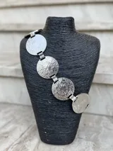 Cinto dorado de metal con eslabones y monedas circulares texturadas.