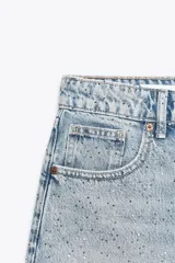 Short de jean negro con lavado gastado y pequeñas estrellas blancas estampadas. Tiene tiro alto, corte recto y terminación desflecada.