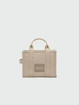 Bolso tote pequeño de lona color azul con estampado frontal de la marca en color blanco y correa de hombro negra.