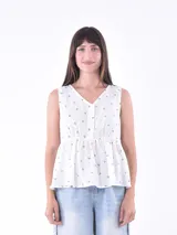 Blusa blanca sin mangas con escote en V y cierre frontal con botones.