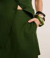 Short pollera de tiro alto color verde oscuro, con corte sastrero y cierre trasero invisible.