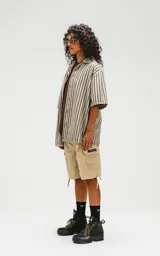 Camisa oversize de manga corta con cuello abierto y estampado a rayas verticales en tonos verde y beige.