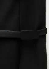 Minifalda negra de corte recto con cinturón decorativo y abertura frontal. Cierre trasero con cremallera invisible.