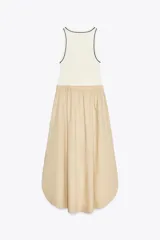 Vestido midi color beige con top blanco de cuello redondo y manga sisa con vivos negros a contraste. Cintura elástica y falda con aberturas laterales.