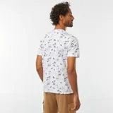 Remera blanca de manga corta con estampado de palmeras y paisajes en azul.