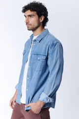 Camisa de manga larga de jean azul claro, con dos bolsillos con solapa abotonada en el pecho.