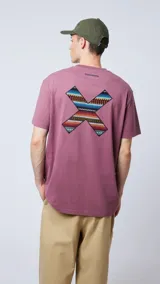 Remera manga corta color lila con cuello redondo y estampado en el pecho con forma de equis (X) con motivos geométricos en colores.