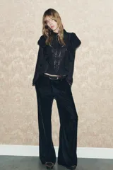 Blusa negra de viscosa con cuello perkins y manga larga. Detalles de bordados, lentejuelas y volantes. Cierre en la espalda con abertura y botones.