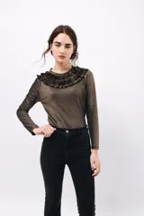 Remera de manga larga confeccionada en tejido de lurex negro con destellos dorados. Detalle de volados en el cuello tipo collar.