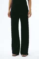 Pantalón de tejido de punto color crema, de tiro alto y pierna ancha, con diseño calado de rombos.