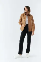 Sobrecamisa color marrón de poliuretano, con cuello clásico, cierre frontal con botones a presión, mangas largas con puños abotonados, dos bolsillos tipo parche con solapa y botón en el pecho.