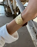 Brazalete ancho de bronce macizo con textura irregular.