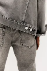 Pantalón de jean gris con efecto lavado, corte regular tapered, tiro medio, cinco bolsillos y cierre con botón y cremallera.