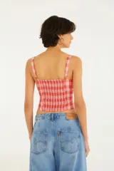Top ajustado con escote recto y tirantes anchos, con estampado a cuadros en tonos rosa y rojo.