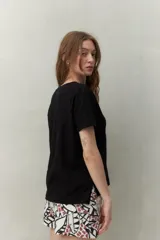 Remera blanca de manga corta confeccionada en algodón liviano con textura levemente jaspeada. Presenta tajos laterales y costura central al frente.