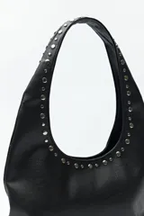 Cartera negra tipo hobo de cuero sintético con apliques de tachas metálicas plateadas en el frente y los bordes.