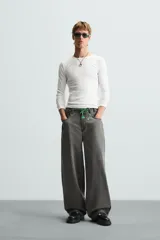 Pantalón de jean gris de corte amplio, estilo balloon fit, con cinco bolsillos, cierre frontal con cremallera y botón, y efecto de color lavado en toda la prenda.