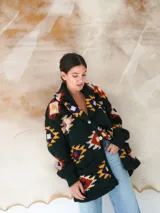 Saco de lana marrón con diseño geométrico multicolor, cuello con solapa, cierre frontal con botones y bolsillos delanteros.