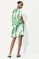 Vestido túnica corto de viscosa con estampado de hojas verdes, cuello mao con abertura en V, mangas cortas, corte holgado y tajos laterales.
