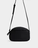 Bandolera negra de cuerina con bolsillo frontal con tag de metal, correa regulable, cierre superior y tirador de material principal.