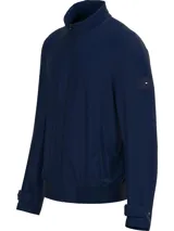 Campera Tommy Hilfiger azul marino de nailon con cuello alto, cierre de cremallera, puños y bajos elásticos, dos bolsillos delanteros y parche con logo en la manga.