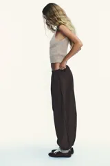Pantalón bombacho marrón de nylon con cintura elástica, bolsillos laterales ocultos y bajo abullonado con elástico.