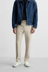 Pantalón slim fit negro confeccionado en tejido con elasticidad en ambas direcciones. Cuenta con bolsillos frontales y traseros de vivo con botón. Cierre frontal con cremallera y botón.