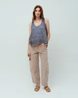 Top sin mangas blanco de lino, con escote redondo, corte en A, ruedo asimétrico y recortes laterales.