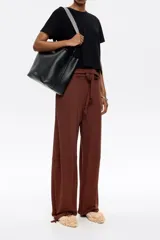 Bolso tote negro de cuero vacuno con doble asa corta y correa de tela extraíble. Interior con tres compartimentos y bolsillo con cremallera. Logo metálico de la marca en el frente.