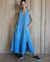 Vestido largo color crudo, sin mangas y con escote en V. Presenta aberturas laterales en el ruedo y bolsillos laterales a la altura de la cadera.