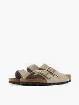 Sandalias Birkenstock Arizona de cuero gamuzado color topo, con dos correas ajustables con hebillas metálicas color cobre y plantilla anatómica de corcho y látex.