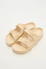 Sandalias planas color beige con doble tira y hebillas ajustables.