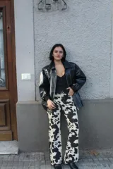 Chaqueta negra de cuero sintético con costuras blancas en contraste, cuello clásico y cierre frontal con botones a presión.