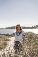 Blusa blanca de algodón con bordados florales en azul marino en el frente y las mangas.