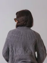 Sweater color crema de tejido de punto con cuello alto y diseño geométrico en la parte superior.