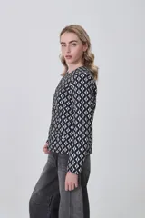 Chaqueta de manga larga con cuello a la base y cierre frontal. Presenta un estampado geométrico repetitivo en blanco y negro.