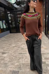 Sweater marrón de tejido de punto con cuello redondo y diseño geométrico en el canesú en tonos rosa, amarillo y gris. De corte clásico y mangas largas.