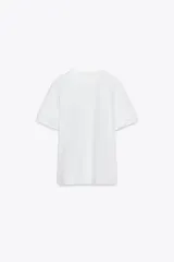Camiseta negra de algodón con cuello redondo, manga corta y detalle de flores con volumen en las mangas.