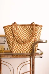 Bolso tipo tote de cuero trenzado a mano en color tostado y beige.