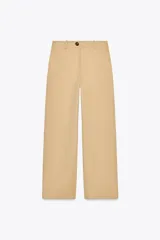 Pantalón color beige de tiro alto con bolsillos delanteros y falsos bolsillos de vivo en la espalda, de pierna ancha y corte recto. Cierre frontal con cremallera y botón.