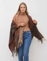 Ruana tejida con diseño colorblock en tonos tierra: marrón oscuro, marrón rojizo y beige claro. Presenta flecos en los bordes.