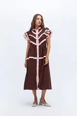 Vestido midi marrón con botones frontales, detalles de volados en mangas y líneas decorativas rosas.