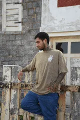 Remera color arena de manga corta con estampa de una mano haciendo el signo de la paz en el pecho. Confeccionada en algodón premium.