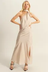 Vestido largo de satén color beige, con escote halter asimétrico y abertura lateral en la falda.