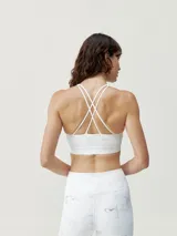 Top deportivo blanco con estampado de mármol gris, de sujeción media. Tiene tirantes finos dobles cruzados en la espalda y copas extraíbles.