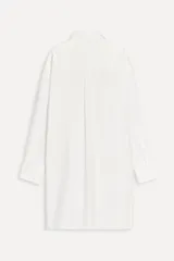 Camisa extra larga blanca de popelín de algodón, con cuello solapa, manga larga con puños, pinzas en la espalda, aberturas laterales y cierre frontal con botones.