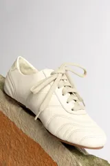 Zapatillas acordonadas color beige con detalles en blanco.