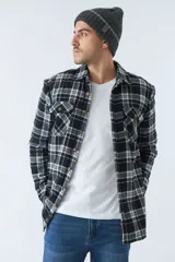 Sobrecamisa de algodón para hombre con interior de corderito, estampado a cuadros en tonos negro, blanco y azul. Tiene cierre de botones, bolsillos tipo cartera y logo en goma. El modelo usa talle M.