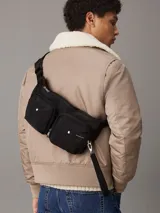 Cartera plegable negra de poliéster reciclado, convertible en bolso de muñeca con correa ajustable.